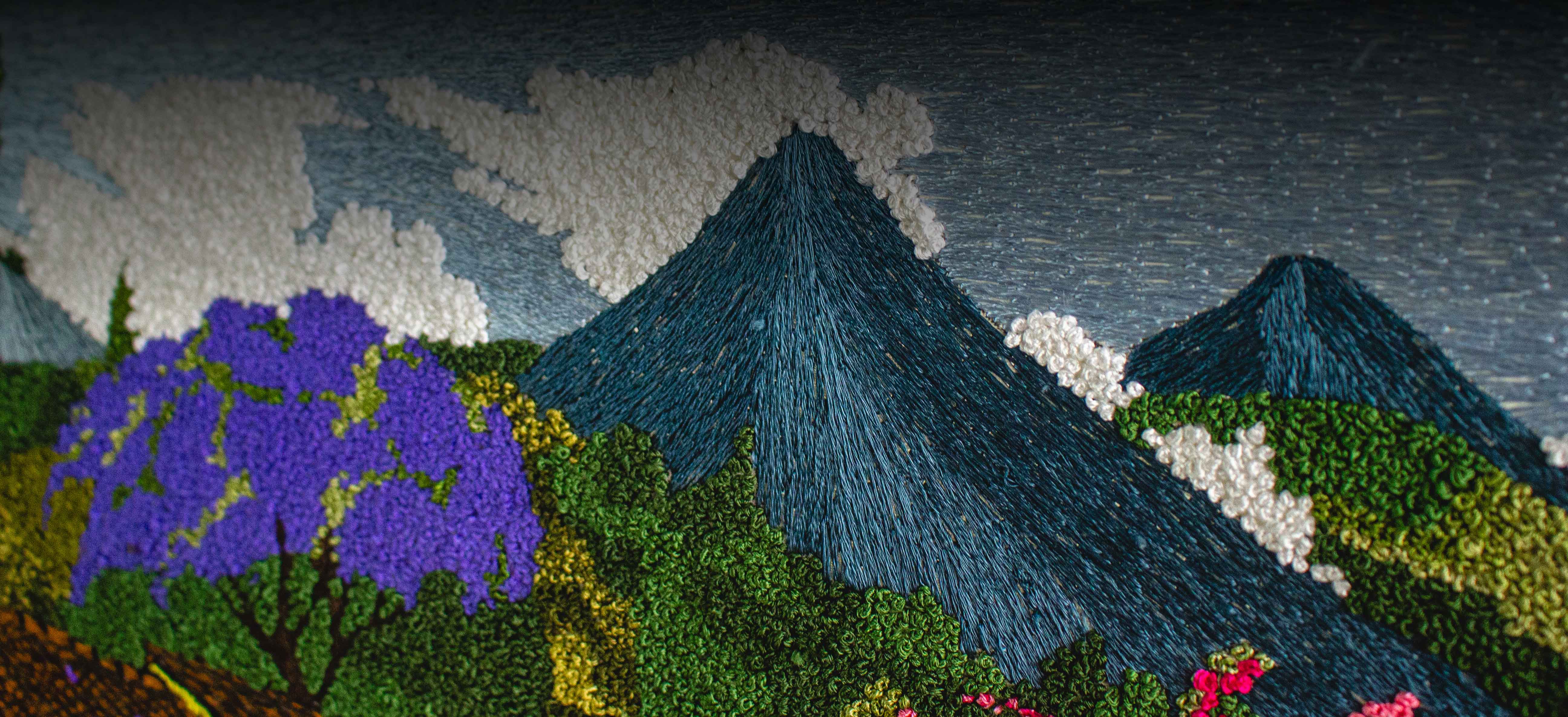 Detalle de una obra bordada a mano con un paisaje guatemalteco