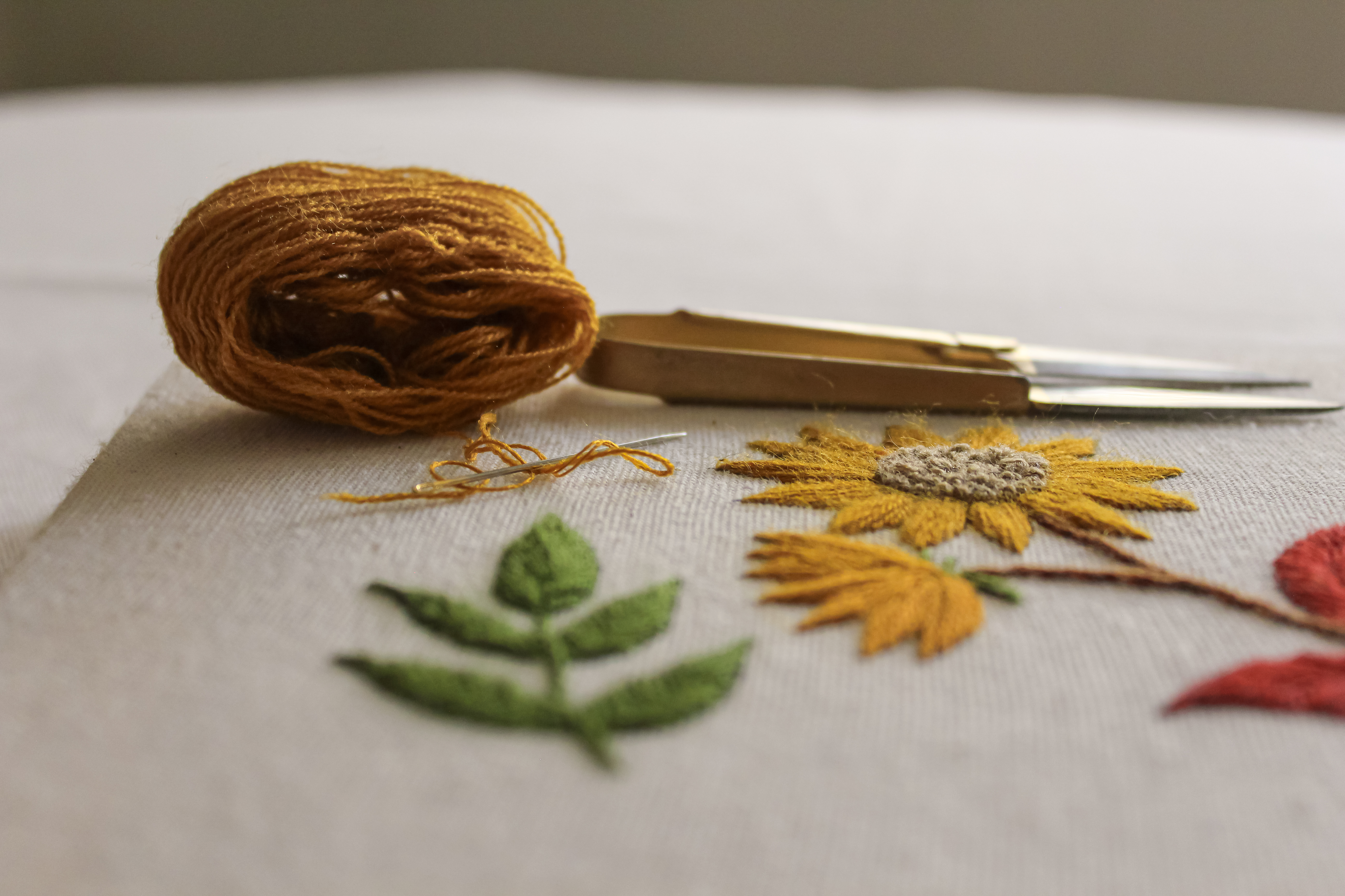 Hilos, tijeras y flores bordadas a mano sobre tela