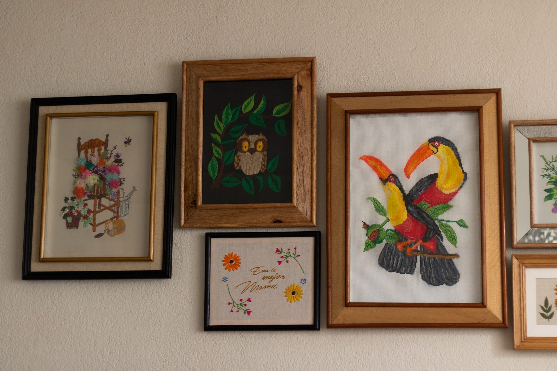 Composición de cuadros bordados y enmarcados sobre una pared