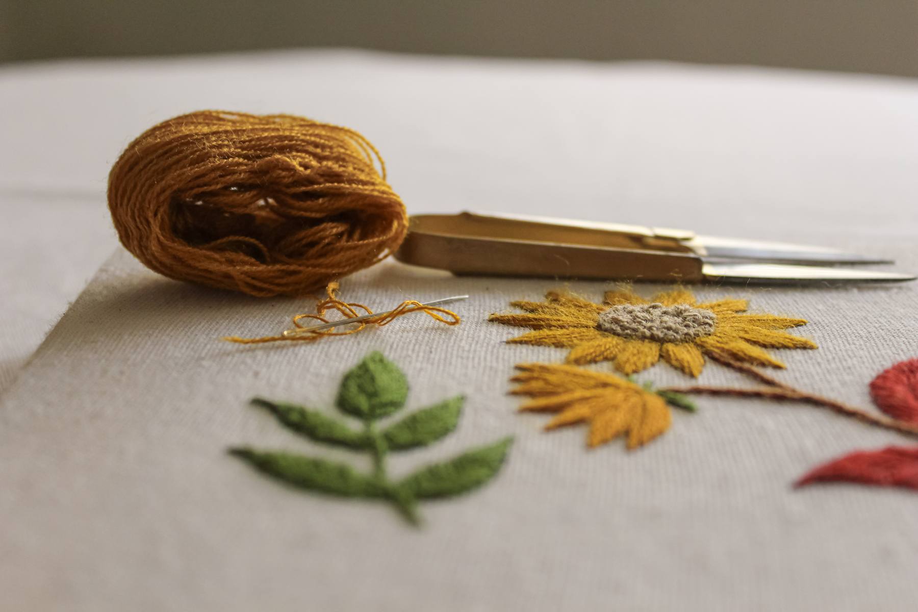 Hilos, tijeras y flores bordadas a mano sobre tela