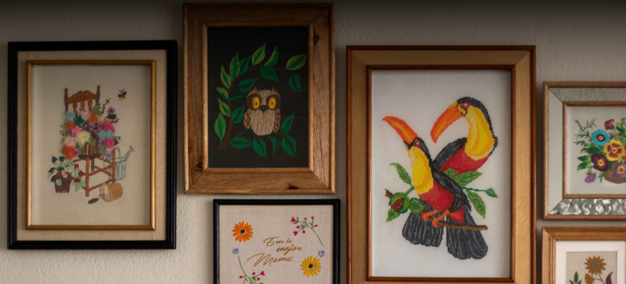 Colección de cuadros bordados y enmarcados por RUGAL, colgados en una pared